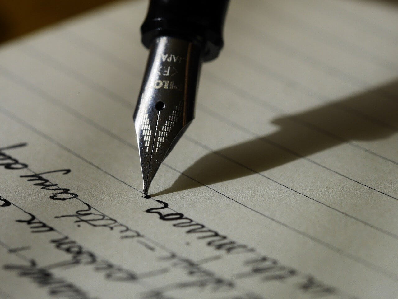 pen writing cursive on paper